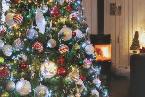 A Christmas tree decorated and set up in a living room with a fire place going. One of the popular stored items in storage units.