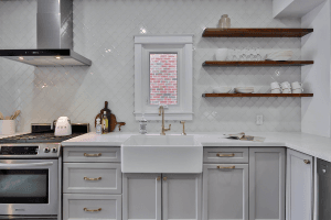 A white kitchen with brown wood shelves holding plates and mugs.