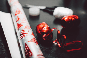 White wrapping paper and red ribbon on a grey table, ready for holiday decor storage.